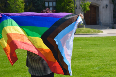 Student holding a Pride Flag outside Johnston Hall