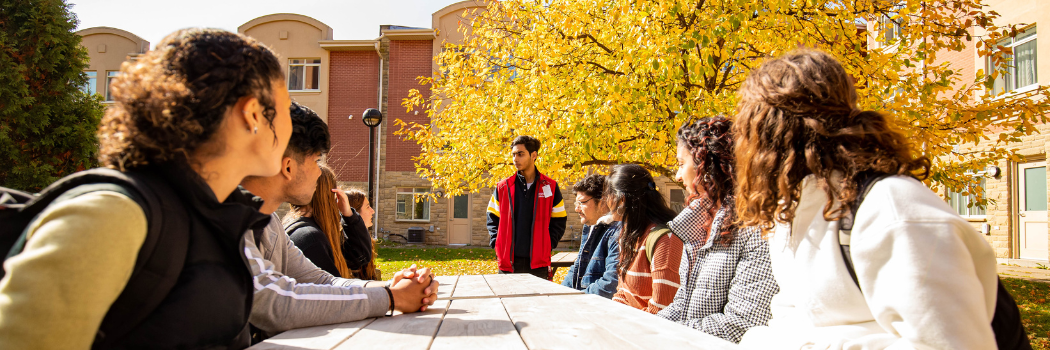 Students talking with an RA at a picnic bench.