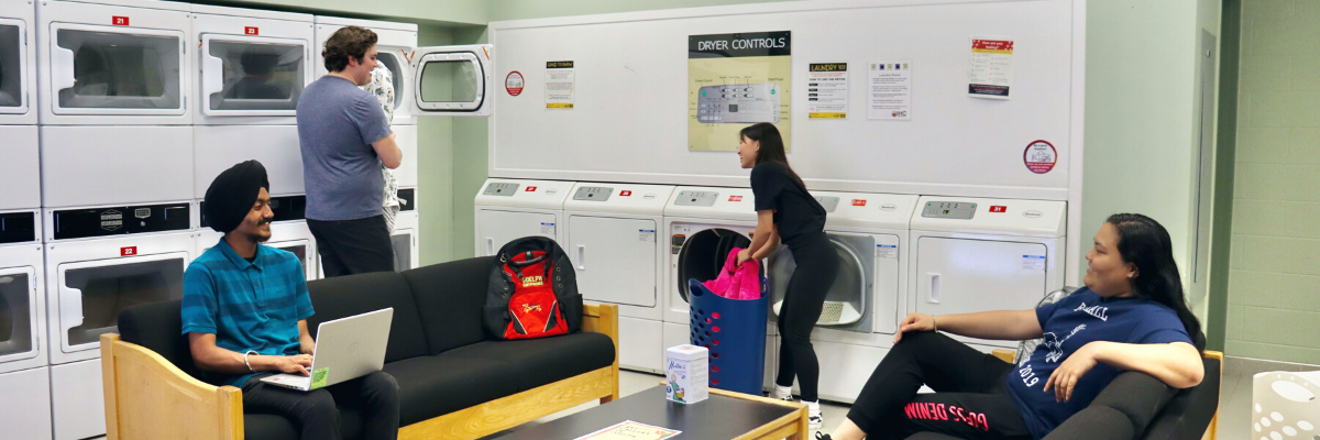 Students doing laundry and having a conversation. 