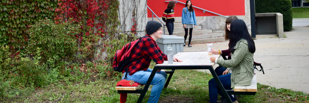 Students sitting at a picnic table outside Mountain Hall. 